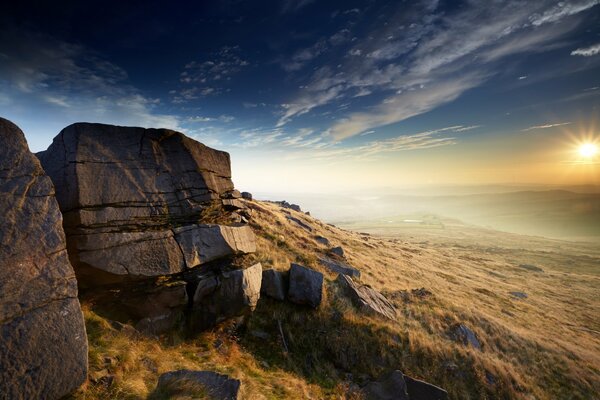 Rocky hills rise above a red field in the sunset rays of a solar star