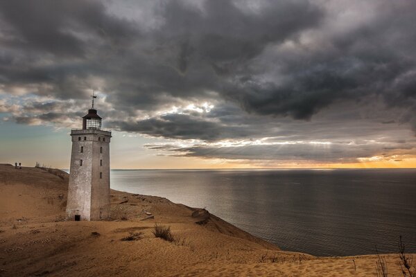 A lonely lighthouse stands on the sandy shore of the sea