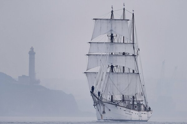 Sailboat during fog in the sea near the lighthouse