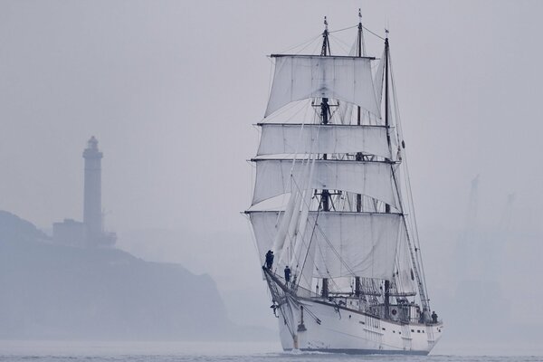 Barca a vela durante la nebbia nel mare vicino al faro