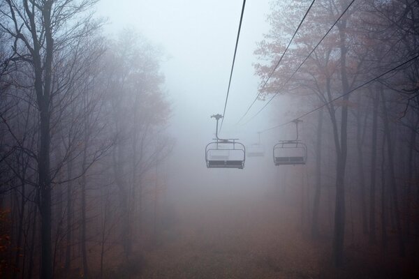 Téléphérique sur le brouillard épais froid de la forêt d automne