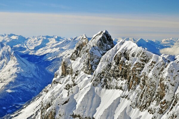 La cima de la montaña se apoya en nubes blancas como la nieve