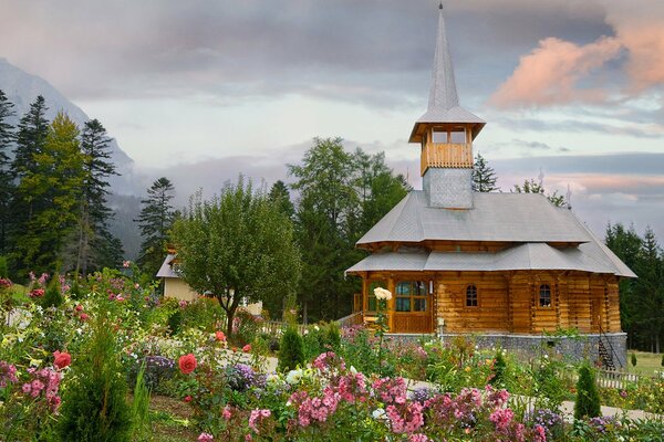 Wooden house with flower beds in summer