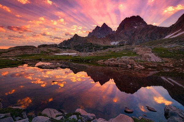 Die Strahlen der Sonnenuntergangssonne brechen über die Berge und strahlen in mehrdimensionalem Glanz