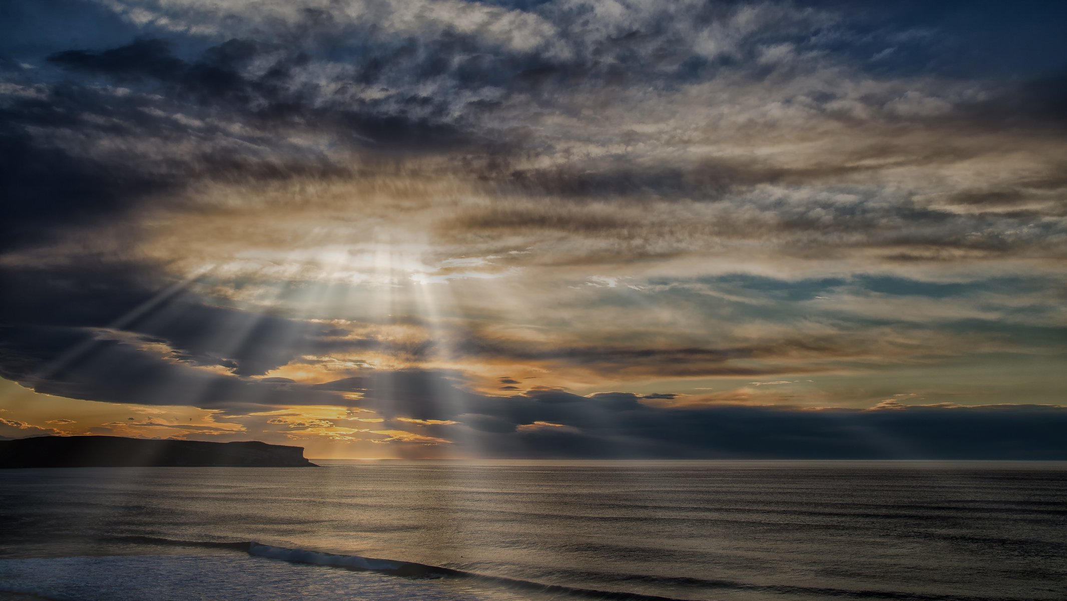 mar roca nubes rayos de sol