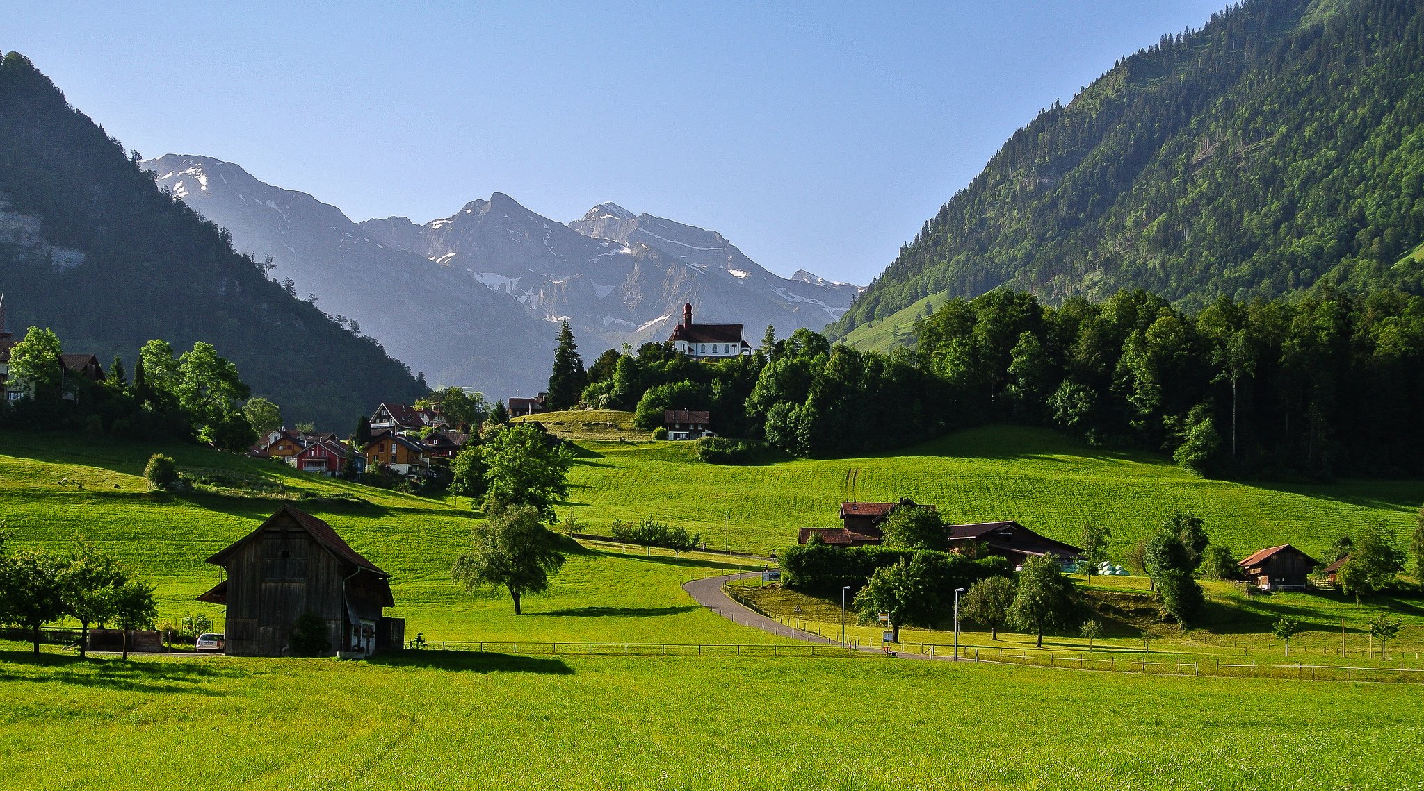 schweiz himmel berge alpen tal gras straße häuser bäume