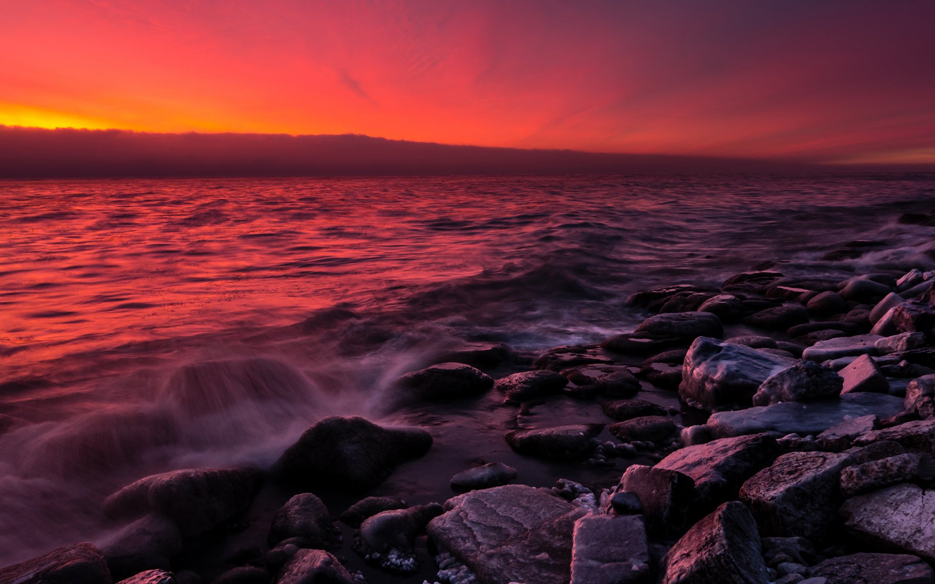 pietre riva sabbia mare onde tramonto nuvole cielo rosso