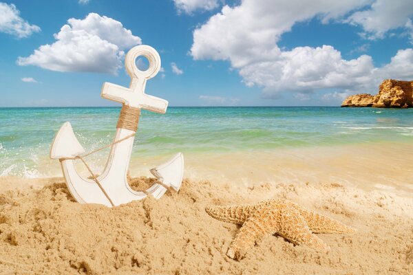 Ancla y estrella de mar en la playa de arena