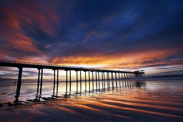 Schöner Sonnenuntergang auf dem Hintergrund der Brücke am Meer