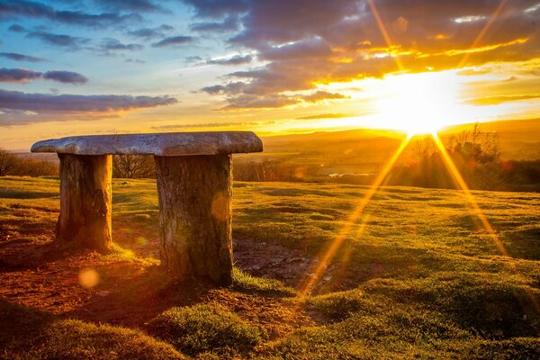 Banc au milieu du champ sur fond de coucher de soleil