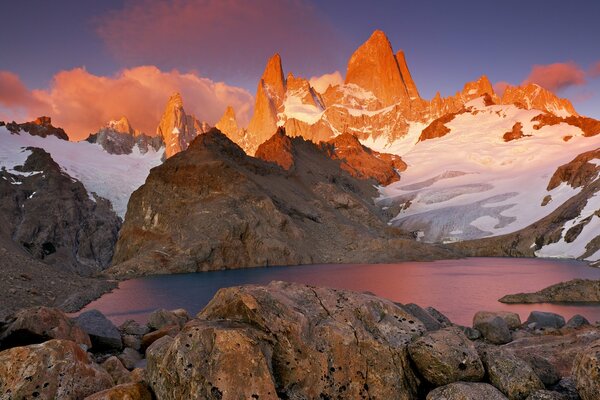 Montañas con nieve alrededor del lago. Atardecer