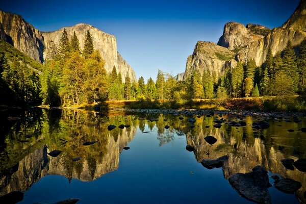 Rocks and autumn forest at the mirror of the lake surface