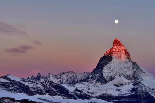 Cima delle Alpi sullo sfondo del cielo crepuscolare. Luna sopra la cima