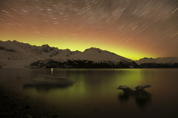 Paysage nocturne du lac entouré de montagnes enneigées