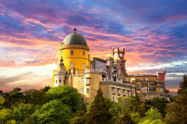 A palace surrounded by greenery against a blue-pink sunset sky