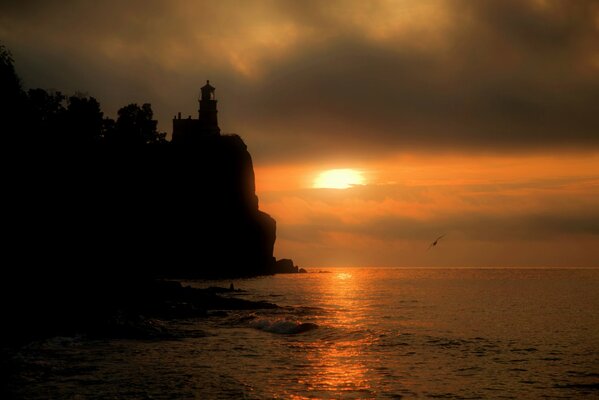 Sunset on the sea at the rock with a lighthouse