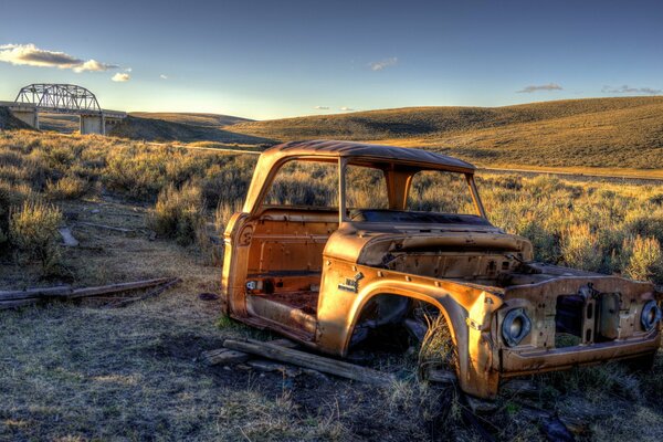 Vieille voiture dans un champ au coucher du soleil