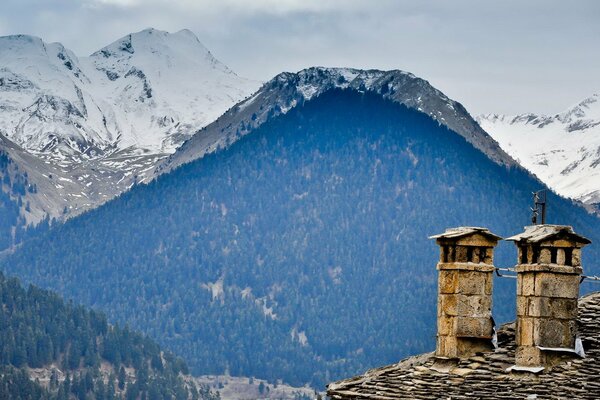 Häuser auf dem Hintergrund der blauen Berge mit Schneekappen