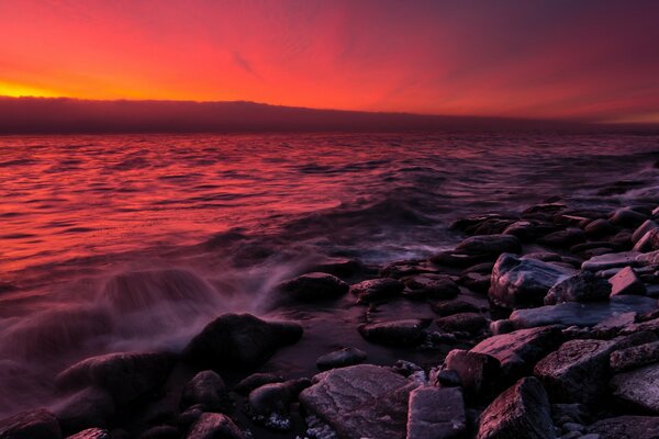 Costa rocosa en medio de una puesta de sol roja