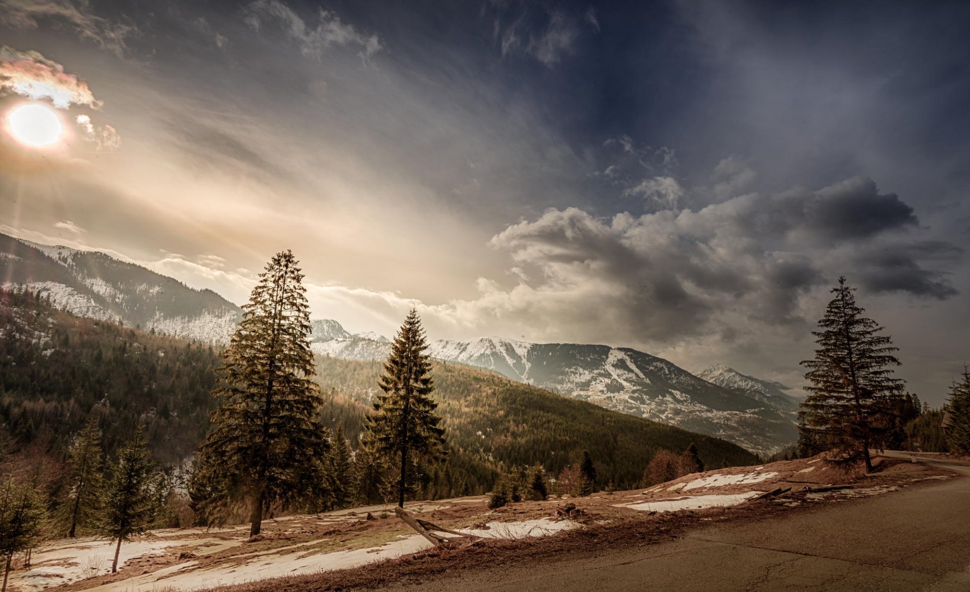 romania tree mountain tops snow sun clouds sky road slope landscape