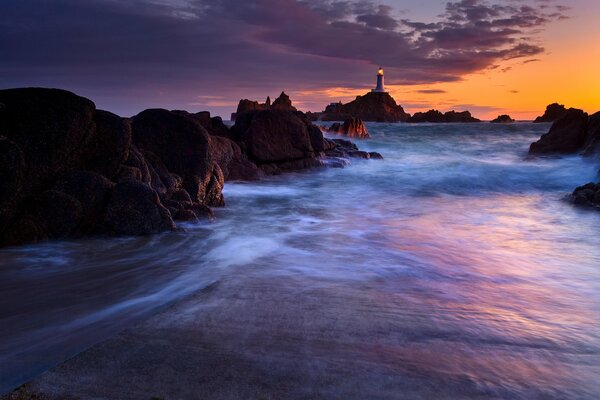 Twilight of the evening sunset with a view of the lighthouse in the sea