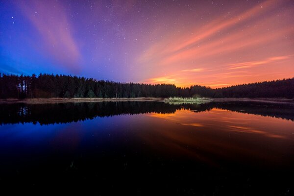 Bäume spiegeln sich bei Sonnenuntergang im Wasser wider