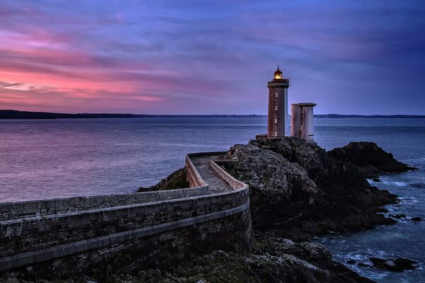 Nichts Überflüssiges am Leuchtturm am französischen Meer auf einem Felsen bei Sonnenuntergang