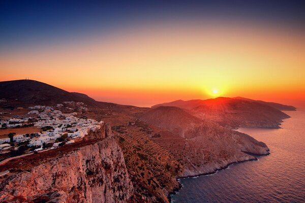 On the cliff there are houses with a view of a beautiful sunset