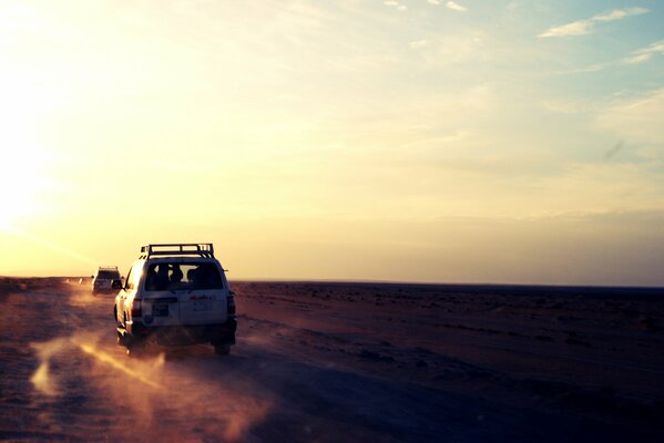 В пустыне по песку едут две машины
