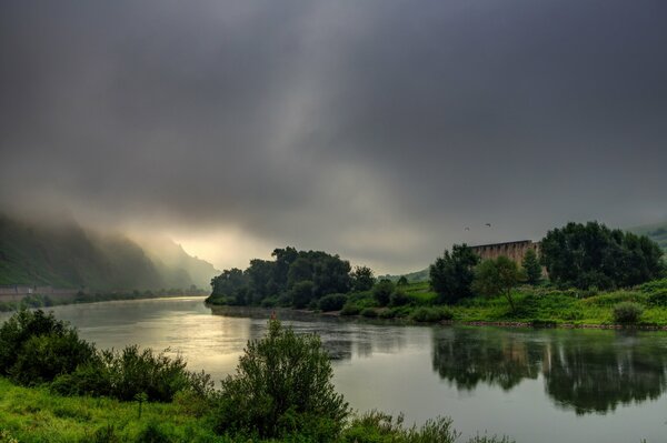 Der Himmel vor dem Regen auf dem Hintergrund des Flusses