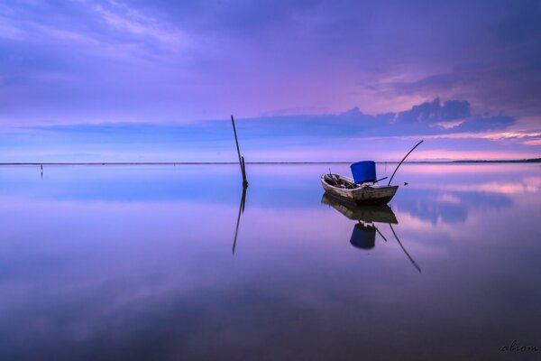 Barca solitaria sullo sfondo di un tramonto lilla
