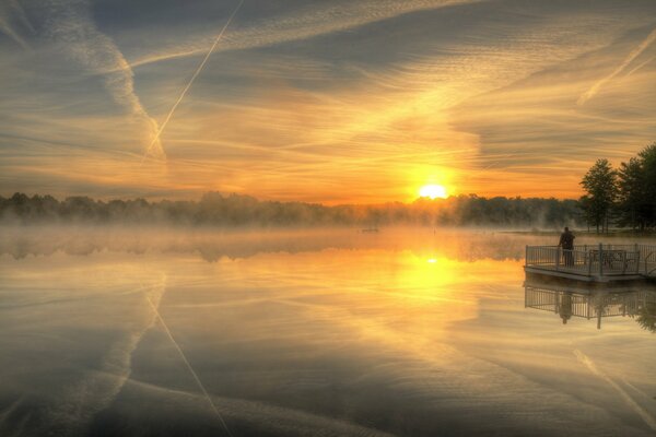 Landschaft mit See und Sonnenuntergang vor Nebelhintergrund