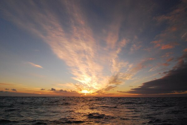 Sunrise at sea with floating clouds