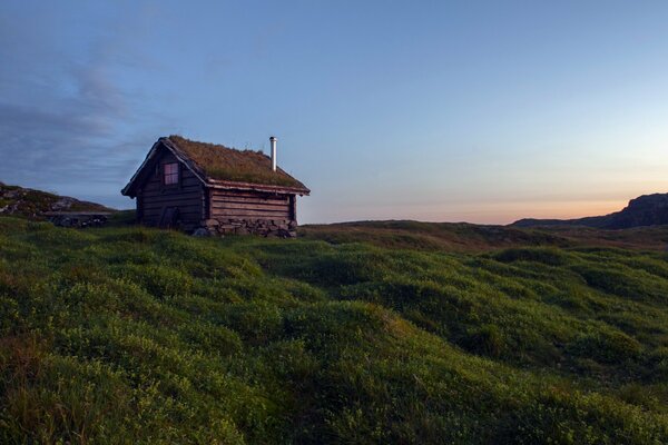 Somewhere in a green field there is a small house with a sunset view from it