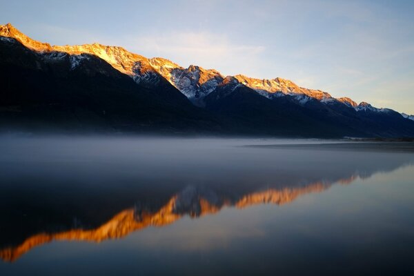 Lago de montaña por la mañana en la niebla