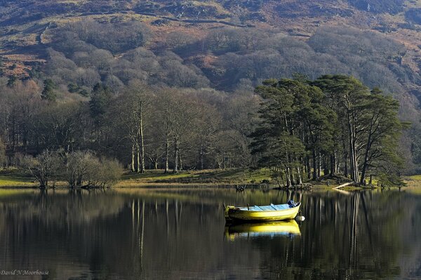 Boat on the lake of spring nature near the hills