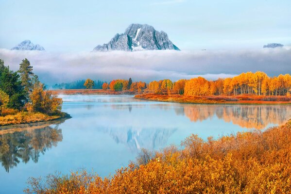 The mountain is reflected in the river among the autumn trees