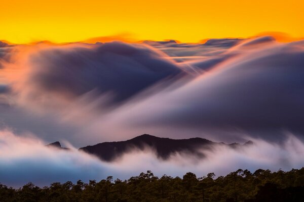 Amanecer de montaña en la niebla de la nube