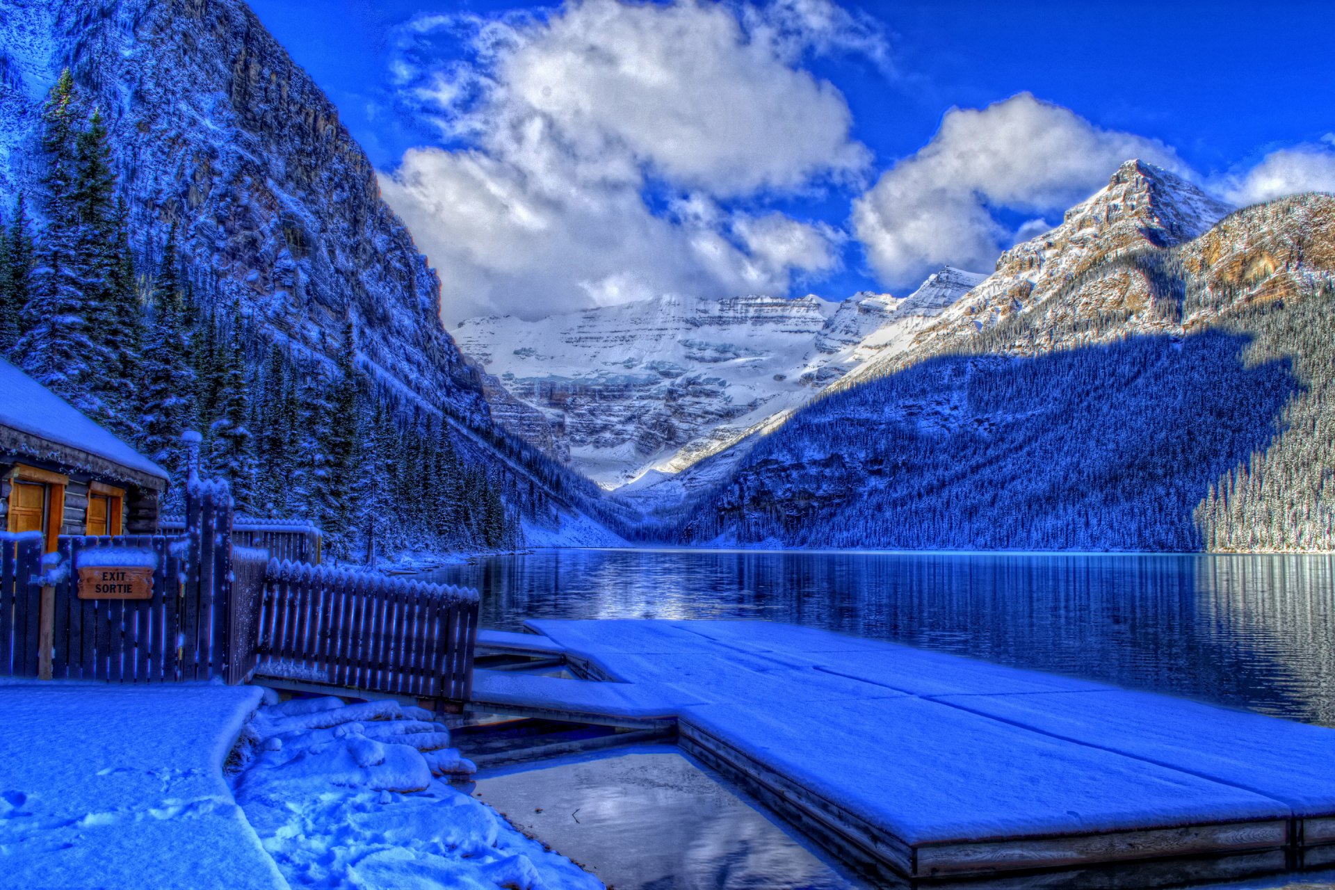 parco nazionale di banff alberta canada inverno neve lago montagne cielo nuvole foresta alberi casetta molo