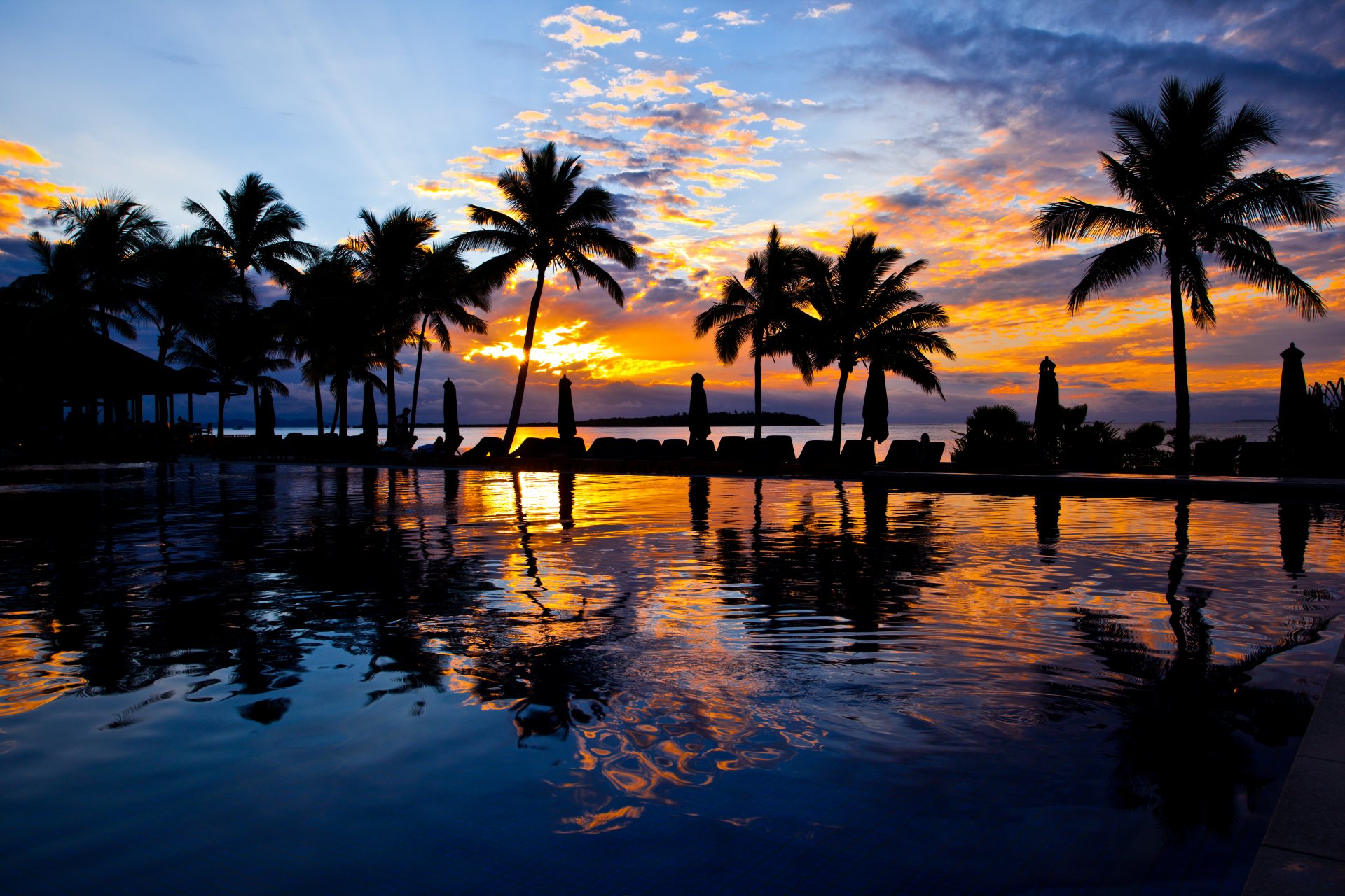 piscine eau palmiers parasols coucher de soleil ciel nuages