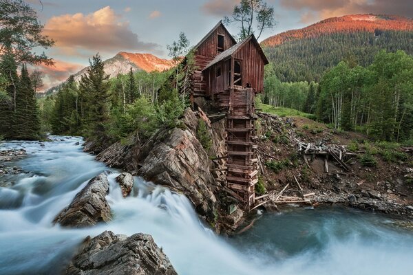 Die Kristallmühle ist bei Sonnenuntergang von einem Abgrund aus Wasser und Wäldern umgeben