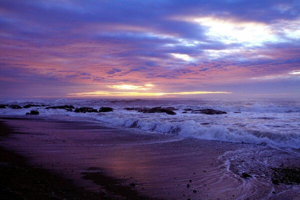 A rocky beach washed by waves in the rays of sunset