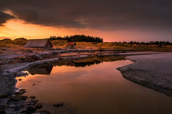 Bei Sonnenuntergang ein Haus am Flussufer