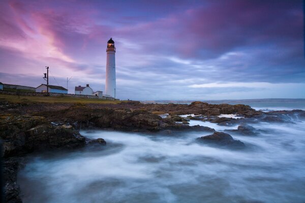 Lighthouse in the foggy ocean with waves