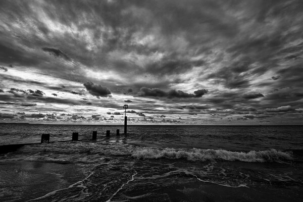 Foto en blanco y negro del océano bajo un cielo nublado