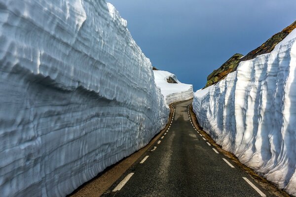 The road going into the distance among the mountain snow-covered rocks