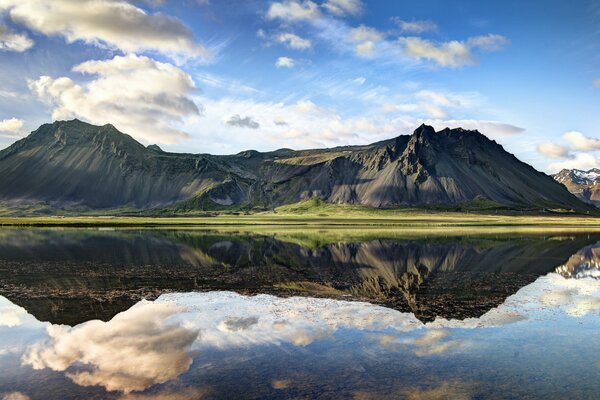 Landscape mountain hills are reflected in the mirror surface of the lake