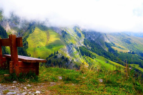 Banco bajo las nubes en el borde de la montaña