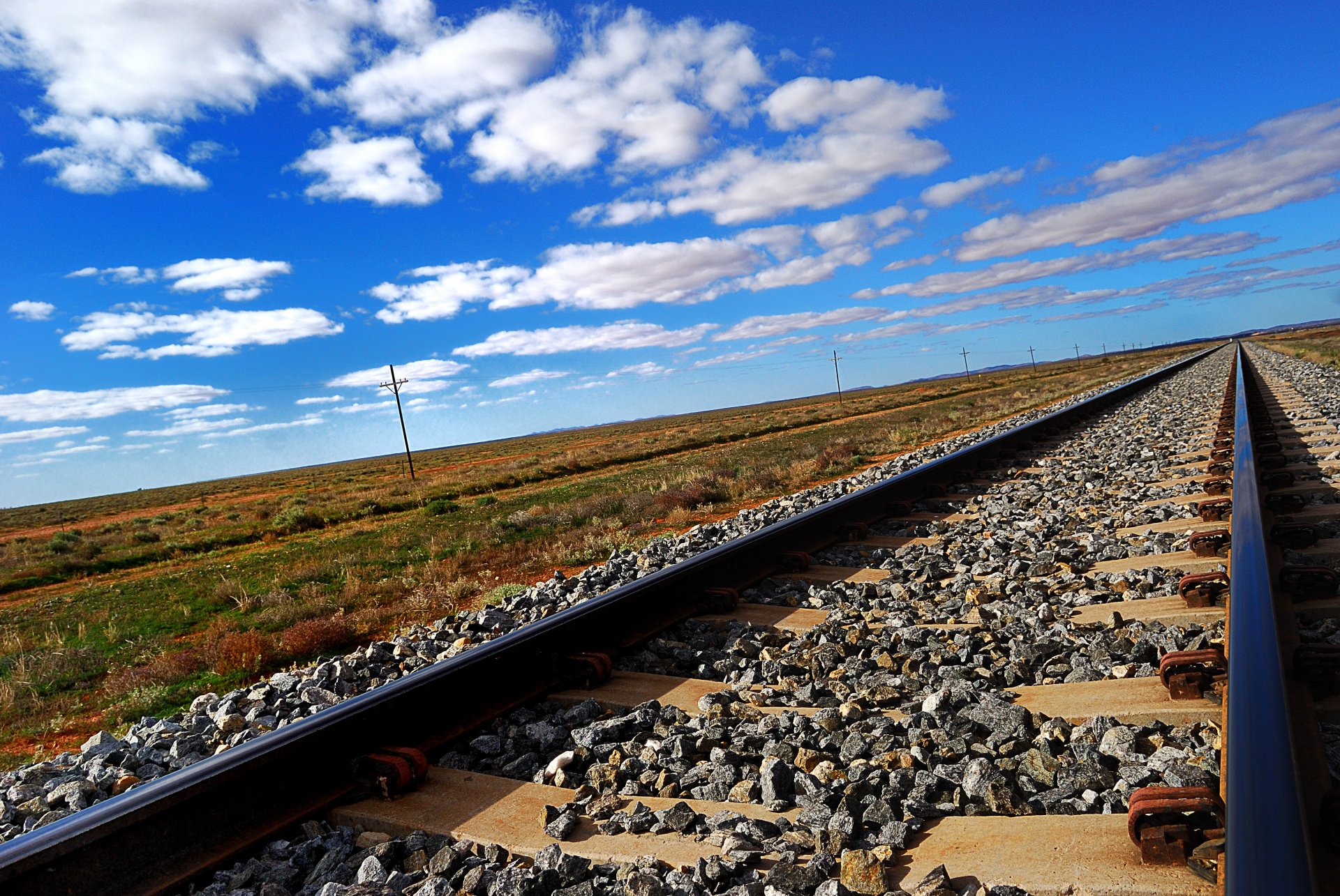 rieles durmientes escombros ferrocarril estepa cielo nubes