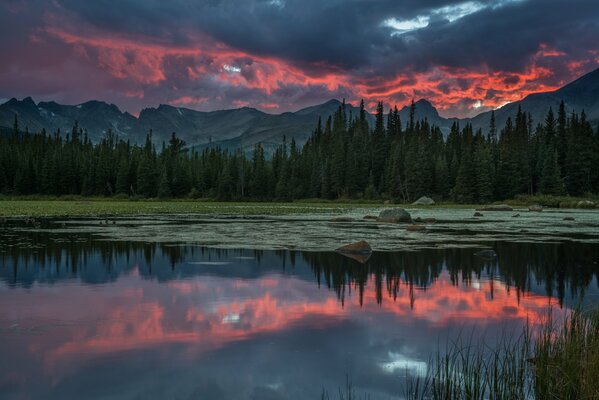 Riflessione di nuvole nel fiume sullo sfondo di montagne e foreste